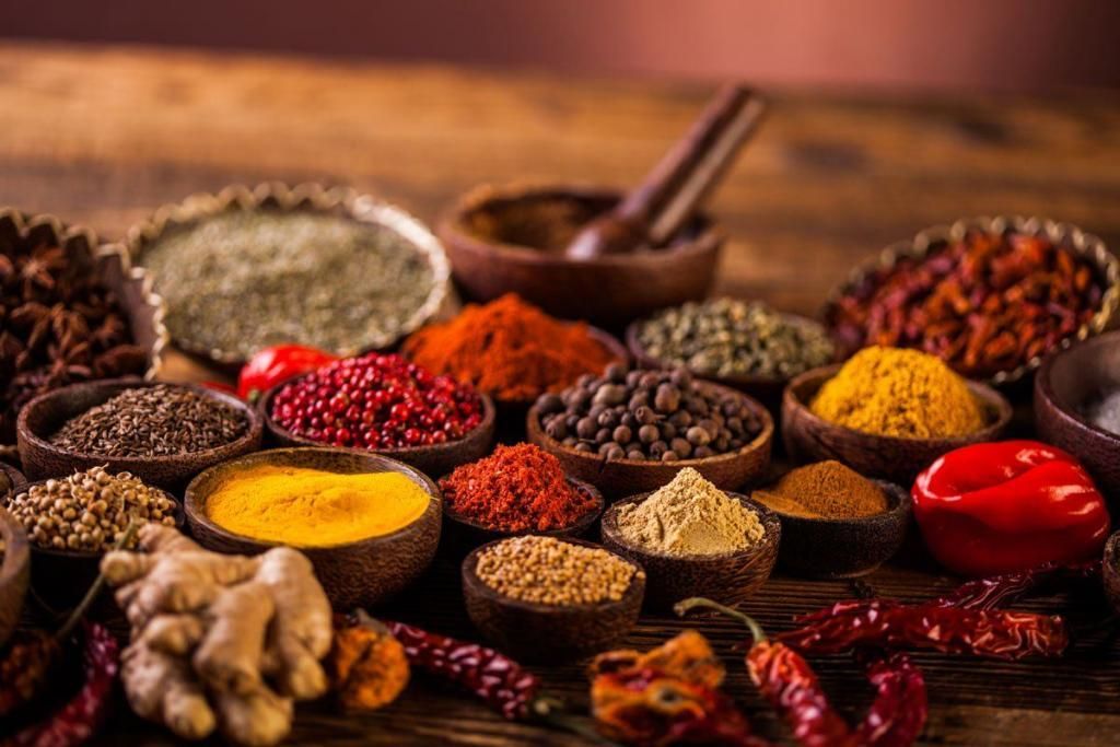 Bowls of ground and whole spices on a wooden table